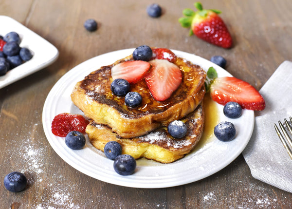 Delicious french toast with fresh fruits and maple sirup. Tasty breakfast scene or dessert with toast, strawberries, blueberries and powdered sugar.