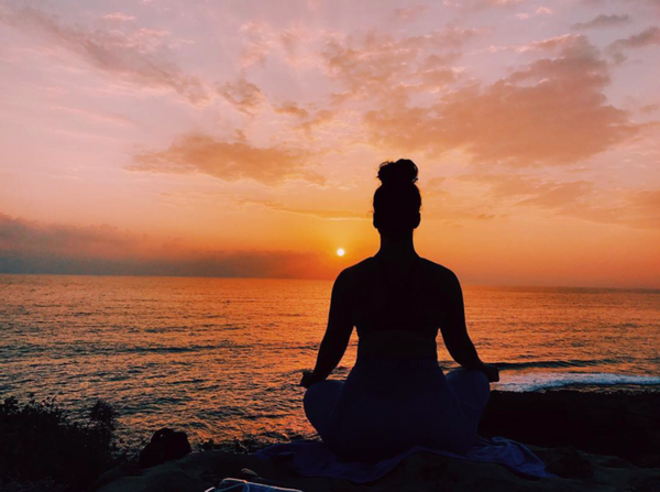 woman practising meditation while viewing the sunset