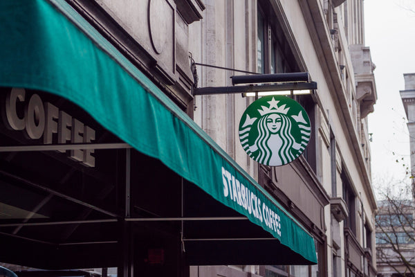 Starbucks street sign over a green awning.