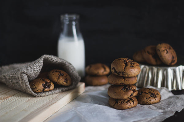 Chocolate chip cookies sitting next to a liter of milk
