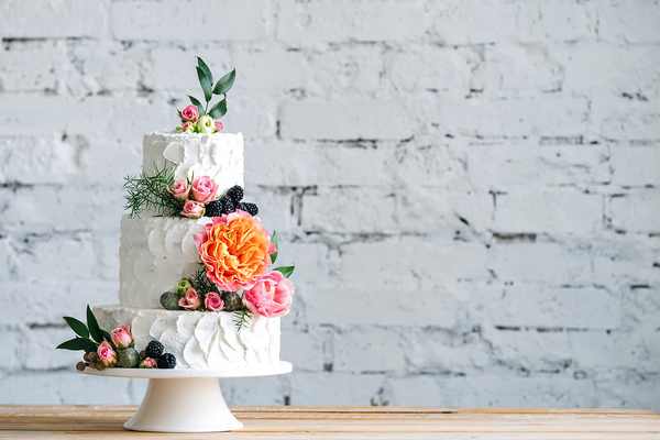 Vegan wedding cake against a white brick wall.